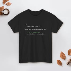 May include: Black t-shirt with white and green text resembling code. The text includes "try", "compileMy Love()", "catch (NullPointerException ex)", and "// I'll handle it initializeRomance();".