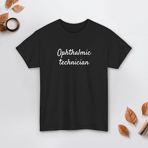 Może przedstawiać: Czarny t-shirt z napisem "Ophthalmic technician" w białym kolorze. Tekst jest napisany kursywą. Koszulka ma okrągły dekolt i wydaje się być wykonana z miękkiego materiału. Tekst jest umieszczony pośrodku z przodu.