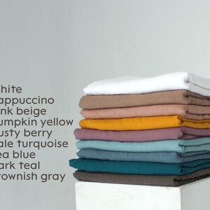 May include: A stack of folded linen fabric in various colors, including white, cappuccino, pink beige, pumpkin yellow, dusty berry, pale turquoise, sea blue, dark teal, and brownish gray. The colors are listed in a column on the left.