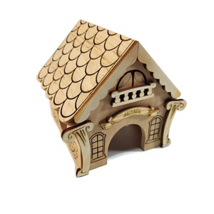 Può includere: Un salvadanaio di legno a forma di casa con un tetto a tegole, una piccola finestra e un cartello che dice "Home".