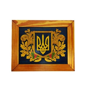 May include: A wooden frame with a blue background and a gold Ukrainian coat of arms with a trident design. The frame is made of natural wood with a light brown finish.