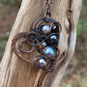 May include: A copper wire heart pendant necklace with a hammered copper heart frame and a cluster of dark gray and iridescent pearls and beads.