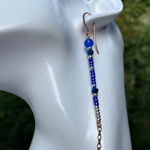 May include: A long, dangling earring with a blue glass bead at the top, followed by silver and blue beads, and a copper chain at the bottom.