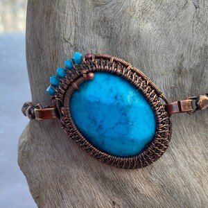 May include: A copper wire wrapped bracelet with a turquoise stone and blue beads.