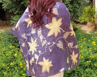 May include: A purple silk scarf with a leaf pattern in shades of yellow and white. The scarf is draped over a person's shoulders.