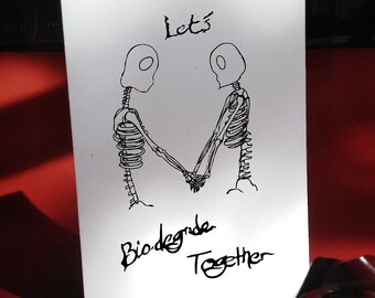 May include: A white card with a black line drawing of two skeletons holding hands. The text "Let's Biodegrade Together" is written below the skeletons.