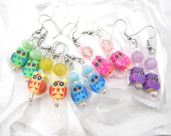 May include: Six pairs of dangle earrings featuring colorful owl charms and crystal beads. The owls are in shades of green, red, yellow, blue, pink, and purple.