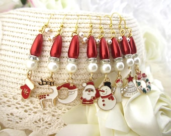 May include: A collection of Christmas-themed earrings with gold-colored hooks. Each earring features a red, pearlescent bead, a faux pearl, and a charm. Charms include a stocking, reindeer, Santa, snowman, angel, Christmas tree, and wreath.