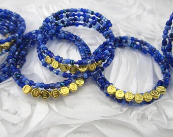 May include: A set of blue and silver beaded bracelets with gold lettering spelling out "FREEDOM".