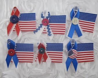 May include: An assortment of patriotic-themed ribbon bows and American flag patches. The bows are red, white, and blue, with decorative buttons. The flags have red and white stripes and a blue field with white stars. Perfect for crafts.