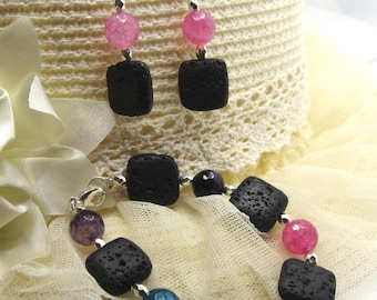 May include: A jewelry set featuring a bracelet and earrings. The bracelet has black square beads interspersed with colorful round beads in shades of pink, blue, orange, and purple. The earrings have pink round beads and black square beads.