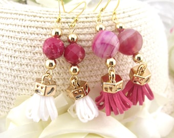 May include: Gold-tone earrings with pink and white accents. Each earring features a gold hook, gold beads, faceted pink beads, a gold cube, and a tassel. One pair has white tassels, and the other has pink tassels.