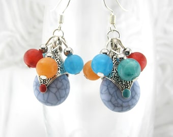 May include: A pair of dangle earrings with silver-tone metalwork and colorful beads. The earrings feature a cluster of red, orange, blue, and green beads, with a large, round, blue-gray stone at the base.