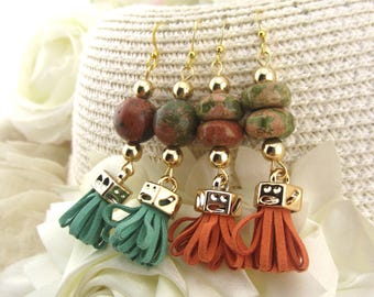 May include: Close-up of three pairs of earrings. Each pair features a gold-colored hook, a series of stone beads, and a tassel. The tassels are in shades of green and orange. The earrings are displayed on a white background.