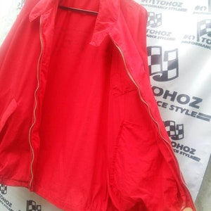 K&ouml;nnte beinhalten: Eine rote Rei&szlig;verschlussjacke mit Kordelzug und einer Tasche auf der linken Seite.