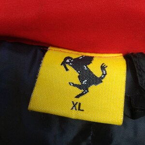 Puede incluir: Etiqueta de ropa amarilla y negra con un logotipo de caballo negro y el texto "XL".