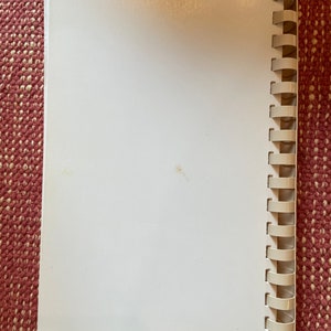 Może przedstawiać: Biały, pusty notes w spirali z białym plastikowym oprawieniem.