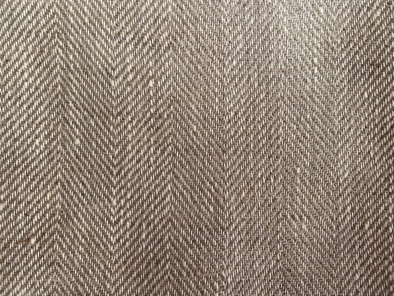May include: Close-up of a brown and white herringbone fabric with a subtle texture.