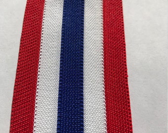 May include: Red, white, and blue striped ribbon. The ribbon is made of a woven fabric and has a slightly textured surface.