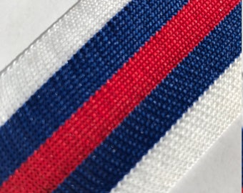 May include: White, blue, and red striped ribbon. The ribbon is woven with a textured pattern.