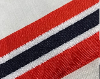May include: Red, white, and navy blue striped trim fabric. The fabric has a knitted texture.