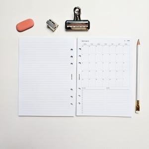 a white notebook with a calendar page, a pen, a stapler, and a pink eraser on a white background.