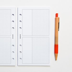 May include: A white, gridded, paper planner with a black border and six holes down the left side. The planner is divided into four sections. An orange pen is lying next to the planner.