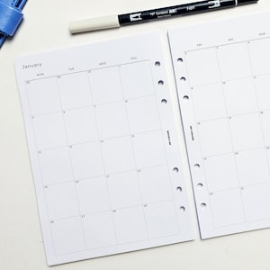 a white-page calendar for January, with a black pen and a blue object on top of it.