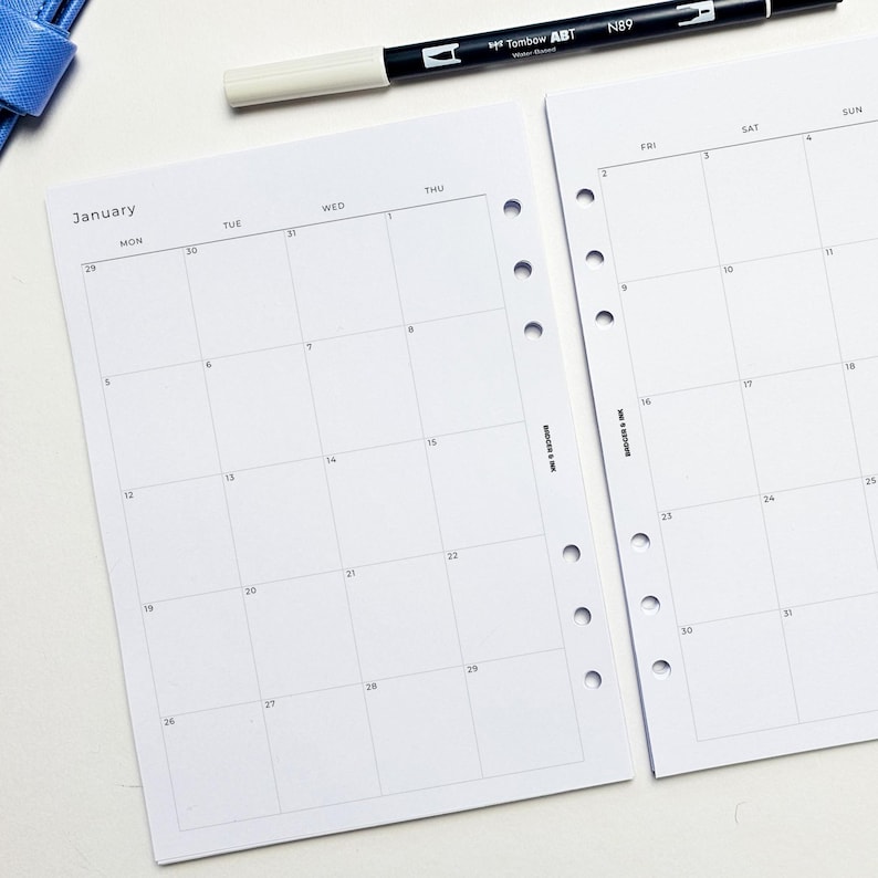 a white-page calendar for January, with a black pen and a blue object on top of it.