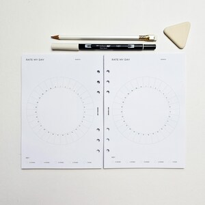 a white binder with two pages, a pen, a pencil, and a small eraser, all arranged on a white surface.