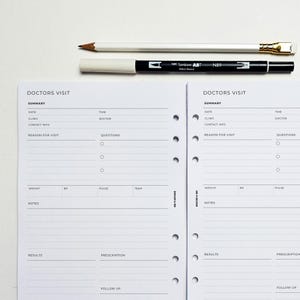 May include: Two-page spread of a doctor's visit planner with a white pencil and a black and white marker on top. The planner pages have sections for summary, date, clinic, contact info, and questions. The text "DOCTORS VISIT" is at the top.