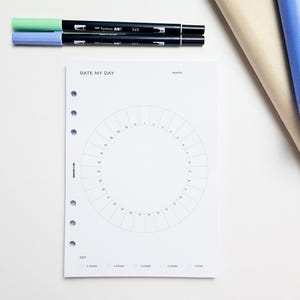 a white paper with a circle design and a key, along with a few pens and markers on a white surface.