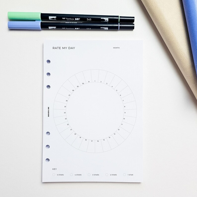 a white paper with a circle design and a key, along with a few pens and markers on a white surface.