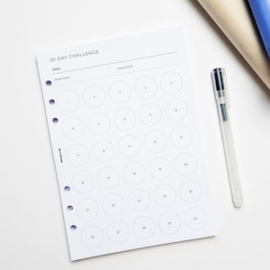 a white paper with a pen and a pen holder on a white surface.
