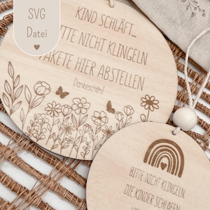 Könnte beinhalten: Zwei runde Holzschilder mit graviertem Text und floralen Designs. Auf einem Schild steht "KIND SCHLÄFT... BITTE NICHT KLINGELN, PAKETE HIER ABSTELLEN, Dankeschön!". Das andere Schild hat einen Regenbogen und lautet "BITTE NICHT KLINGELN, DIE KINDER SCHLAFEN". Beide Schilder haben eine Schnur zum Aufhängen.