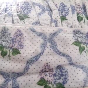 May include: White fabric with a blue and white polka dot pattern and a floral design featuring lilac flowers and blue ribbons.