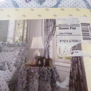 May include: A queen-sized flat sheet in a lilac floral pattern. The sheet is shown on a bed with matching pillowcases and a throw blanket. The sheet is labeled "Queen Flat" and "Lilac Cottage".