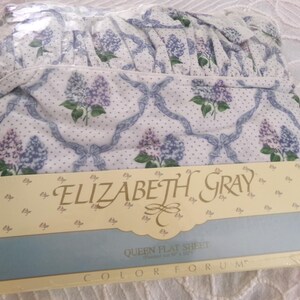 May include: A white queen flat sheet with a blue and white floral pattern. The sheet is packaged and labeled "Elizabeth Gray" and "Color Forum".
