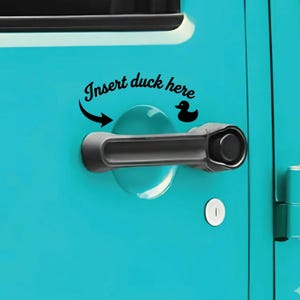 May include: A black vinyl decal applied to a bright turquoise vehicle door, positioned above a black door handle. The decal features the black text "Insert duck here" in a cursive font, accompanied by a curved arrow and a small black duck silhouette.