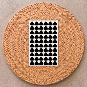 May include: A rectangular white sticker sheet featuring a repeating grid pattern of solid black triangles. The sheet contains ten rows and six columns of identical black triangle shapes arranged in a uniform, organized layout on a flat surface.