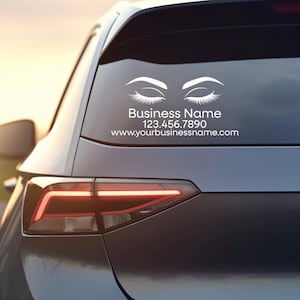 May include: A white vinyl decal applied to a car rear window featuring a graphic of two closed eyes with long eyelashes. Below the graphic, the text reads Business Name, 123.456.7890, and www.yourbusinessname.com in a clean sans-serif font.