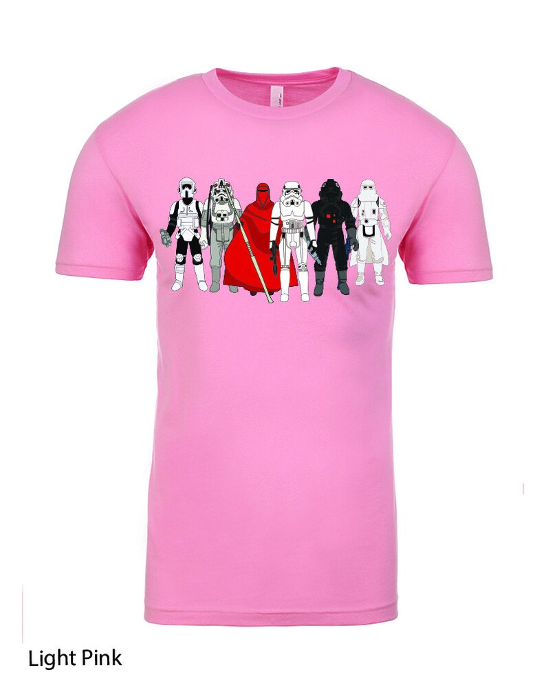 Puede incluir: Una camiseta rosa claro con un gr&aacute;fico de personajes de Star Wars, incluyendo Darth Vader, un Stormtrooper y un soldado rebelde.