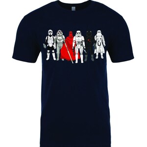 Puede incluir: Una camiseta azul marino con un gr&aacute;fico de siete personajes de Star Wars, incluyendo Darth Vader, un Stormtrooper y una figura con una capa roja.