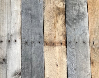 May include: Close-up of a wooden surface with five vertical planks of wood. The planks are different shades of gray, brown, and beige. The wood has a rustic, weathered look.