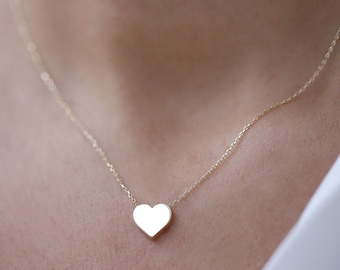 May include: A delicate gold chain necklace with a small, flat heart pendant.