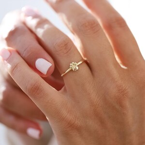 May include: A gold ring with a paw print design. The ring is worn on a person's finger.