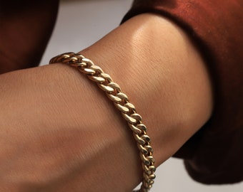 May include: A gold chain bracelet with a curb link design.