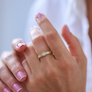 K&ouml;nnte beinhalten: Ein Goldring mit einem kleinen herzf&ouml;rmigen Diamanten in der Mitte. Der Ring befindet sich an einem Finger.