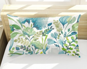 May include: Two white pillowcases with a blue and green floral pattern. The pillowcases are on a white bed with a white headboard.