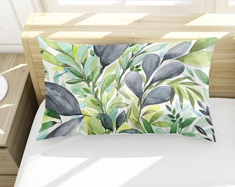 May include: Two white pillowcases with a watercolor pattern of green leaves and gray flowers. The pillowcases are on a white bed.